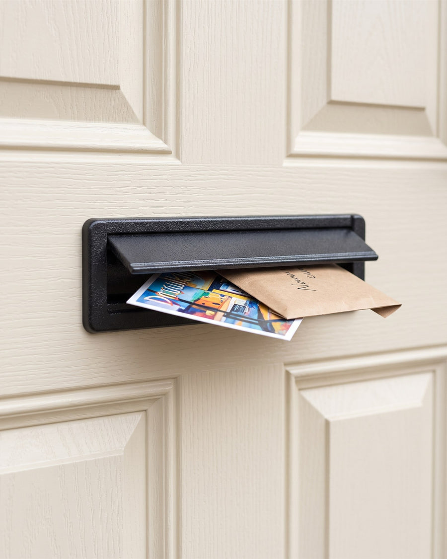 Antique black telescopic letter plate on a cream composite door with a postcard and envelope in the flap
