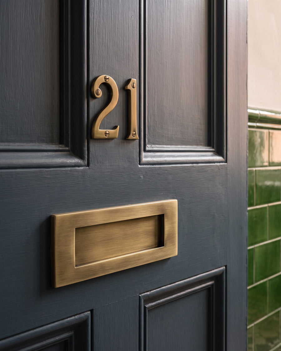 Antique brass screw-on numbers 21 above an antique brass letter plate on a blue-grey tenement flat door