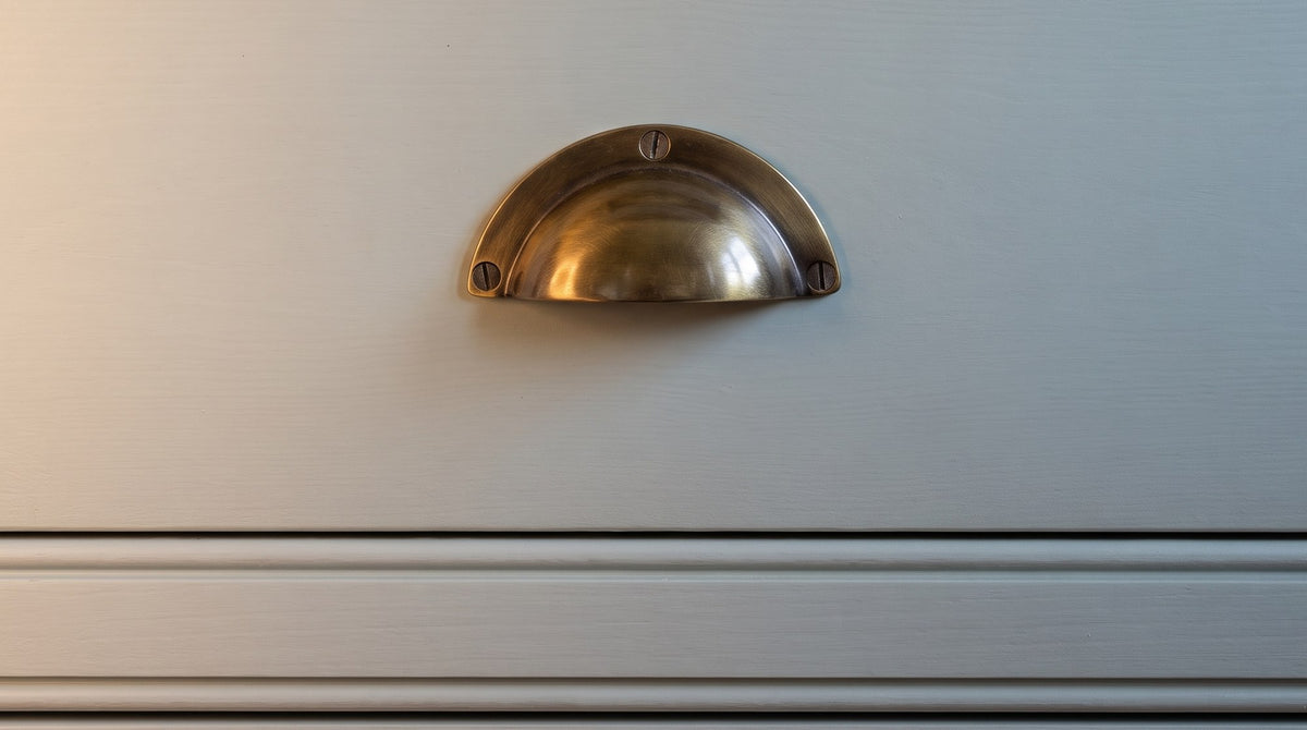 Antique brass hooded cup pull on a blue-grey green painted in-frame kitchen drawer