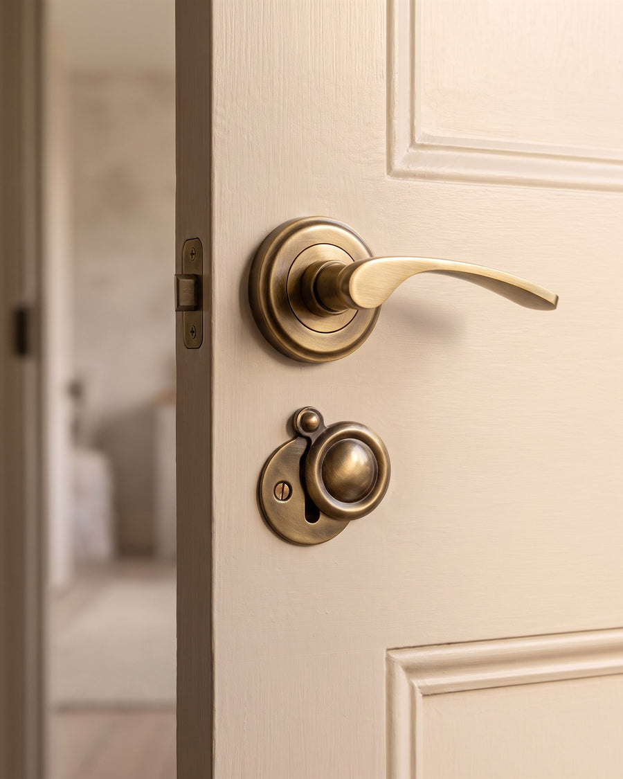 Antique brass Sophia lever on rose with an antique brass covered key escutcheon directly below it, near the opening edge of a mushroom painted shaker door