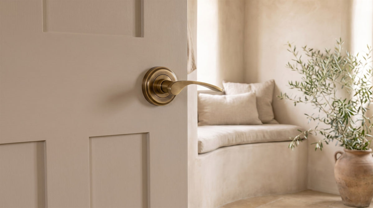 Antique brass Sophia lever on rose on a mushroom-painted door against limewashed walls