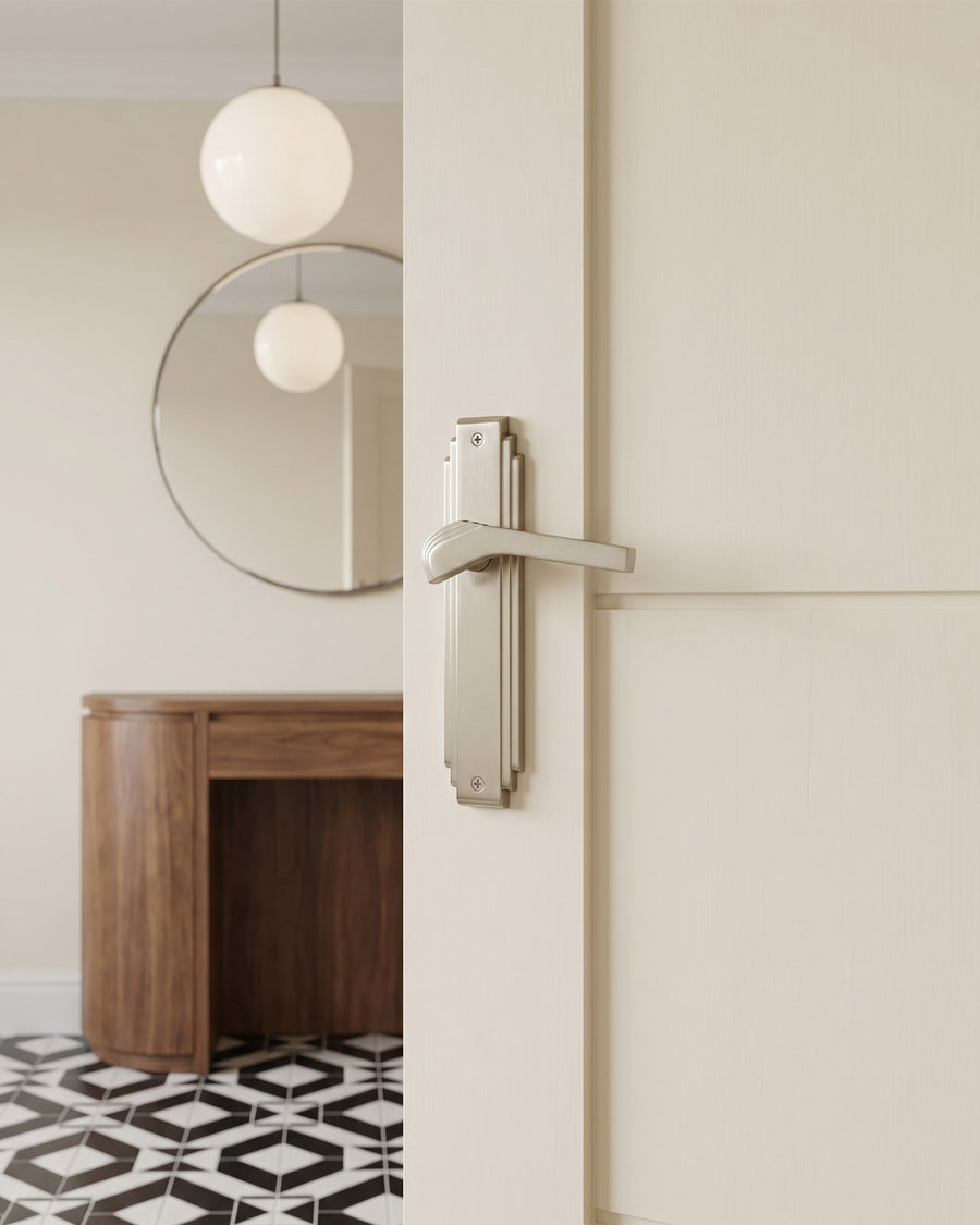Art Deco hallway with geometric black and white tiles, a walnut console, globe lights and a satin nickel Tiffany lever on a cream door