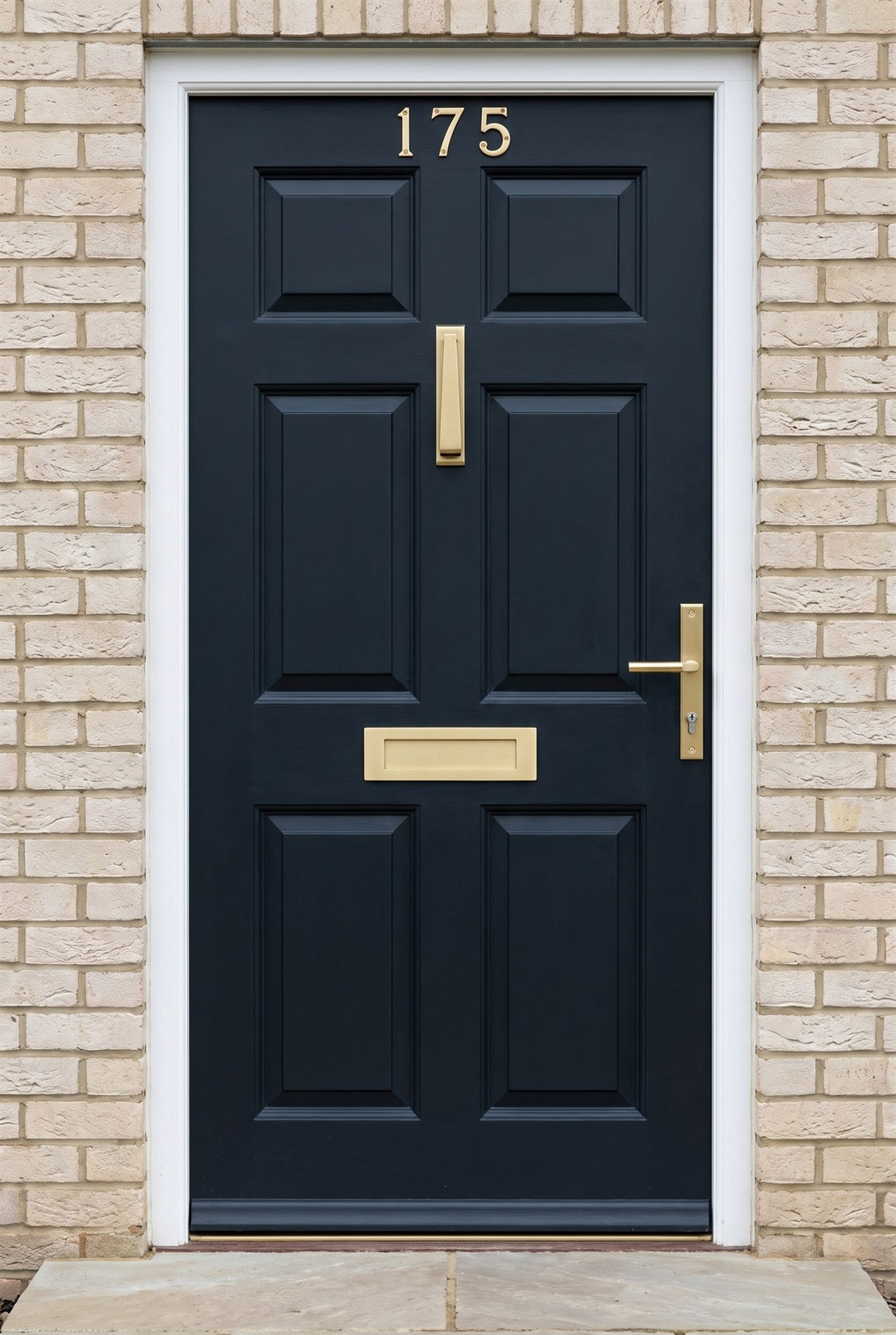 Blue-black six-panel front door with satin brass house numbers, slim knocker, letter plate and Bauhaus multipoint handle