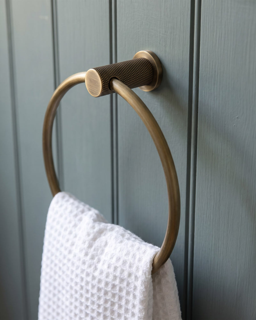 Knurled antique brass Brunel towel ring with a white waffle hand towel on grey-blue tongue-and-groove panelling