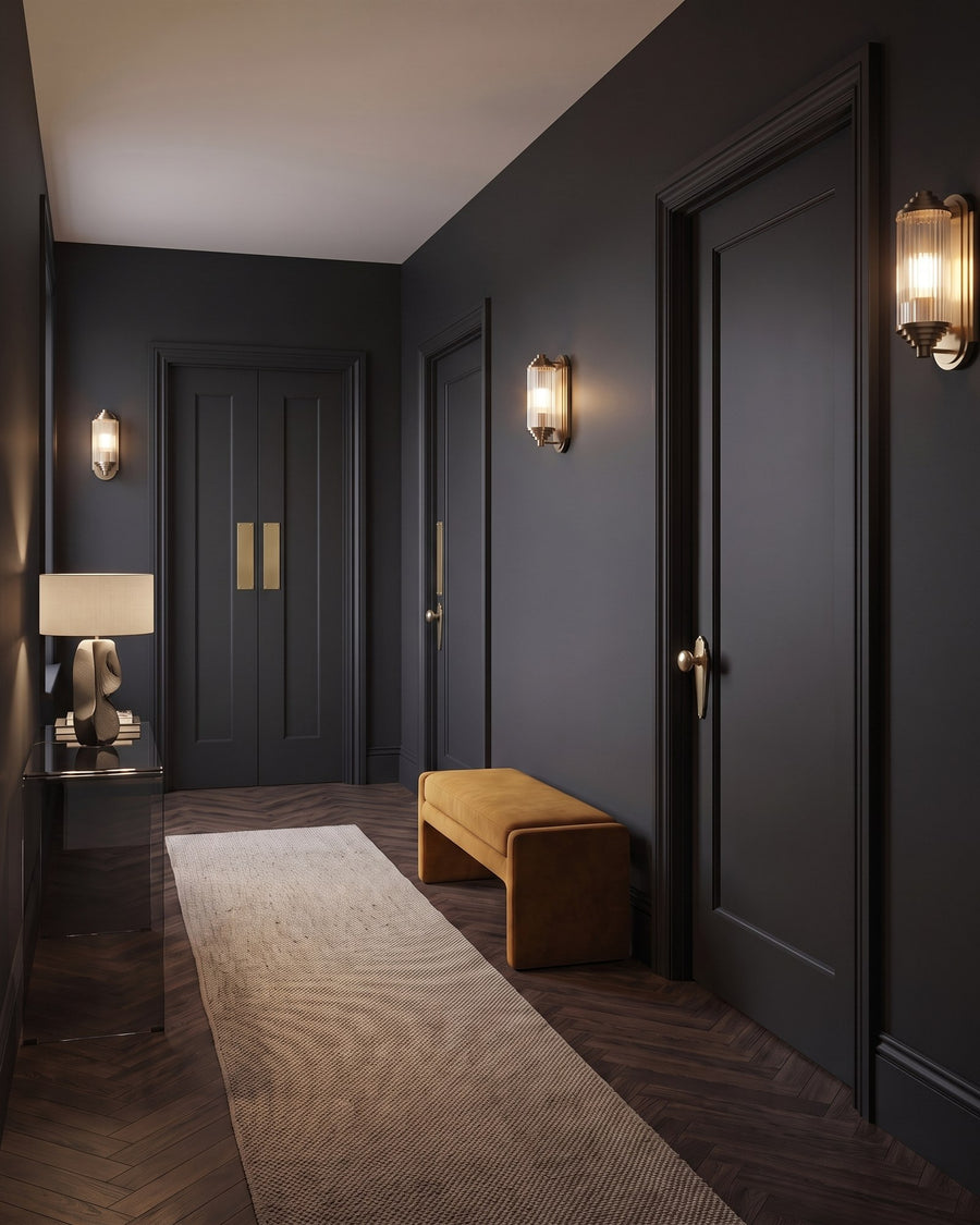 Charcoal colour-drenched landing with Broadway knobs on the bedroom doors and satin brass push plates on the drawing room double doors, ochre velvet bench and brass wall lights
