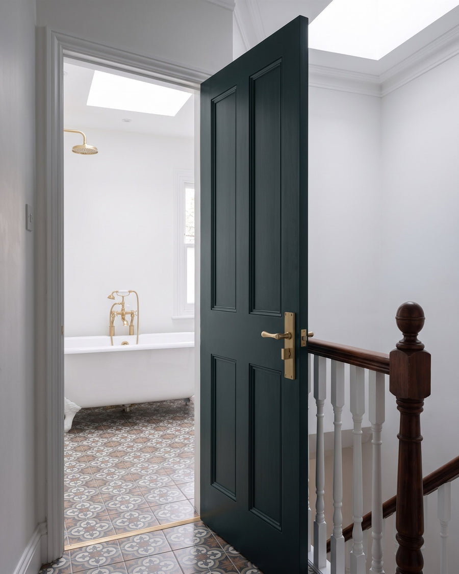 Inky green bathroom door open off a landing with a mahogany newel, fitted with a satin brass Charlbury reeded bathroom handle, a roll-top bath beyond
