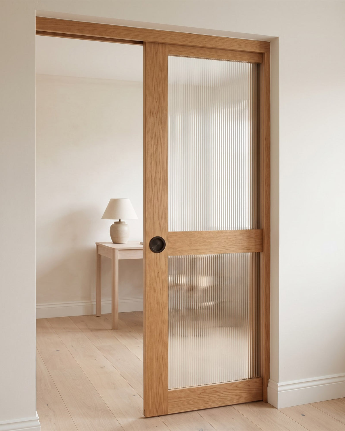 Oak and fluted glass sliding screen door with a dark bronze circular flush pull, opening onto a small study