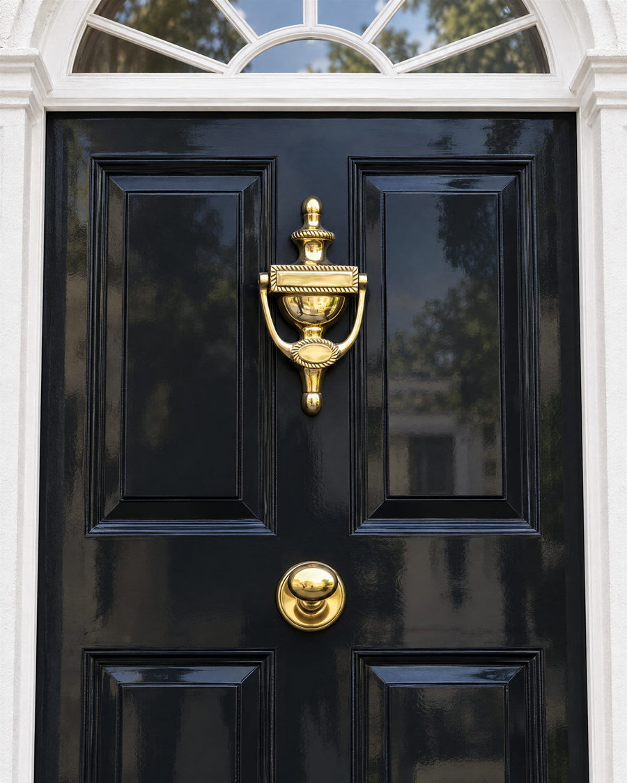 Polished brass Georgian urn door knocker above a round centre knob on a black door