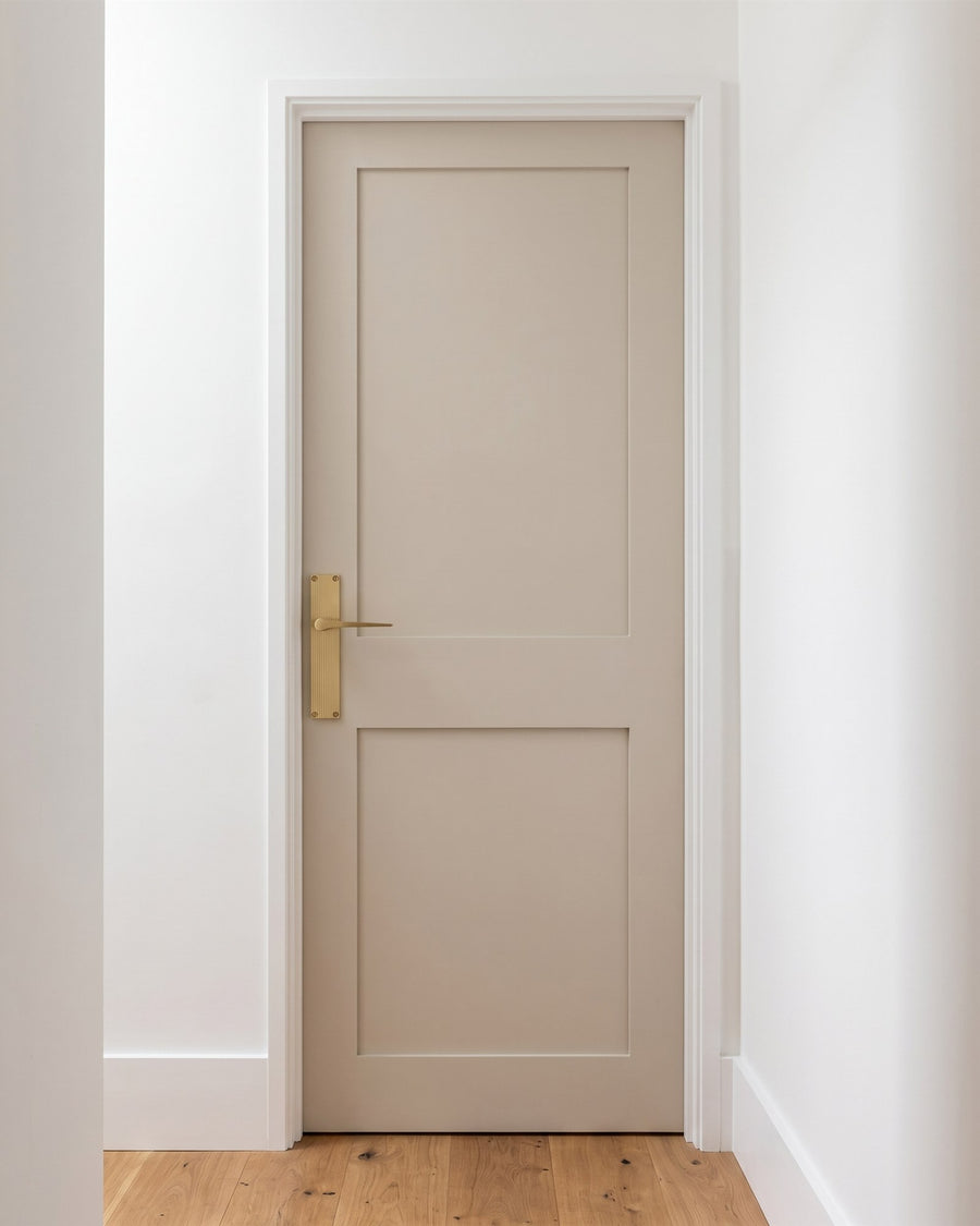 Gio reeded satin brass lever on a reeded backplate on a putty painted two-panel hinged door