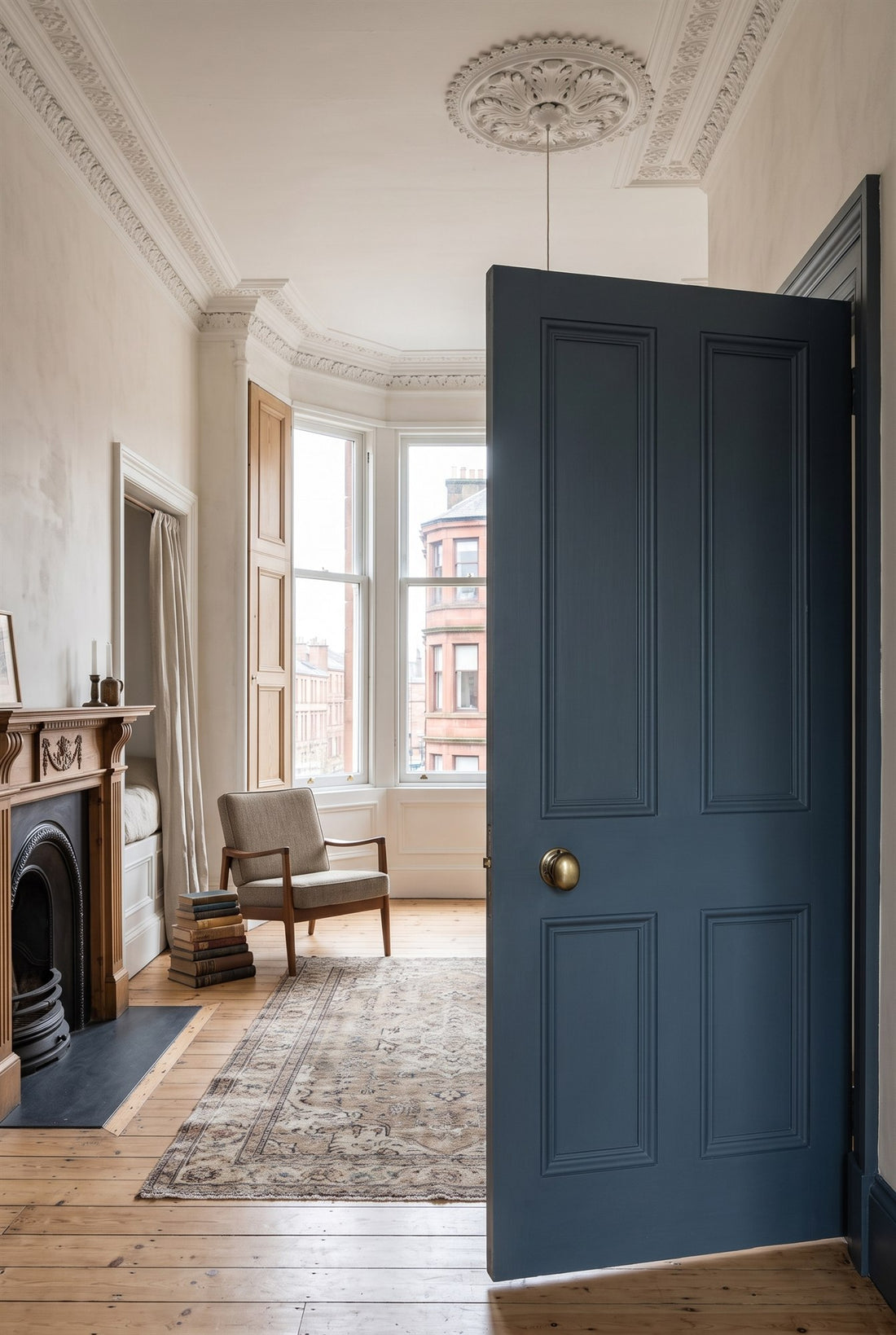 Glasgow tenement front room with cornicing, a shuttered bay window and box bed, and a tall blue-grey panelled door with an antique brass Victoria knob