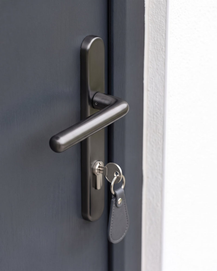 Graphite Windsor lever on its rounded backplate with a key and grey leather fob in the euro cylinder