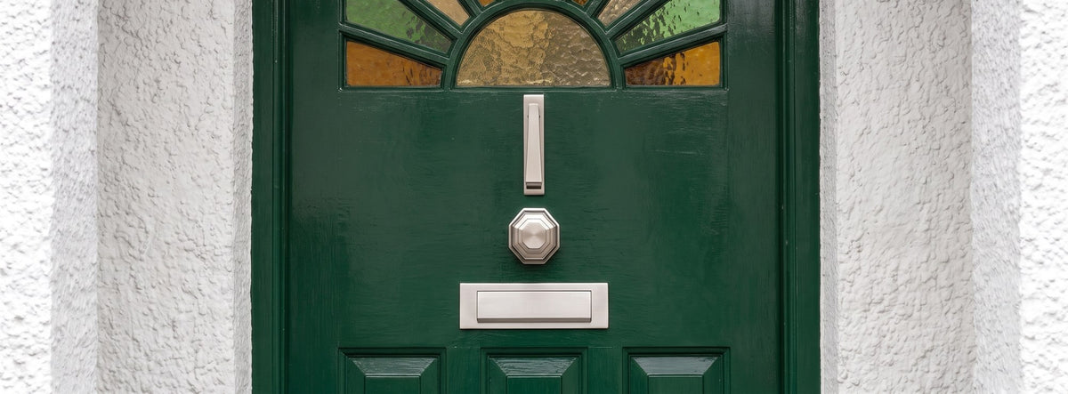 Green gloss 1930s sunburst front door in a white rendered arched porch, with a satin nickel slim knocker, octagonal centre knob and letter plate