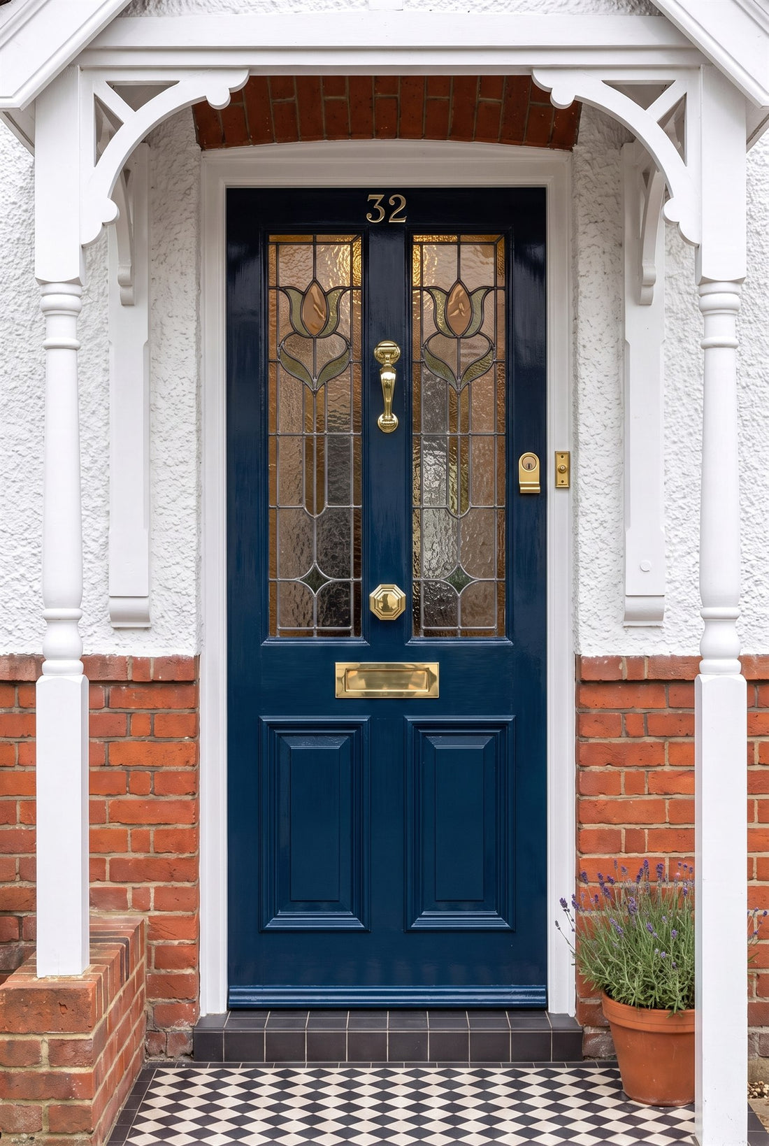 Inky blue gloss Edwardian front door with Art Nouveau stained glass under a timber porch, fitted with polished brass number 32, profile doctor knocker, octagonal centre knob, letter plate, radiused cylinder pull and rectangular bell push