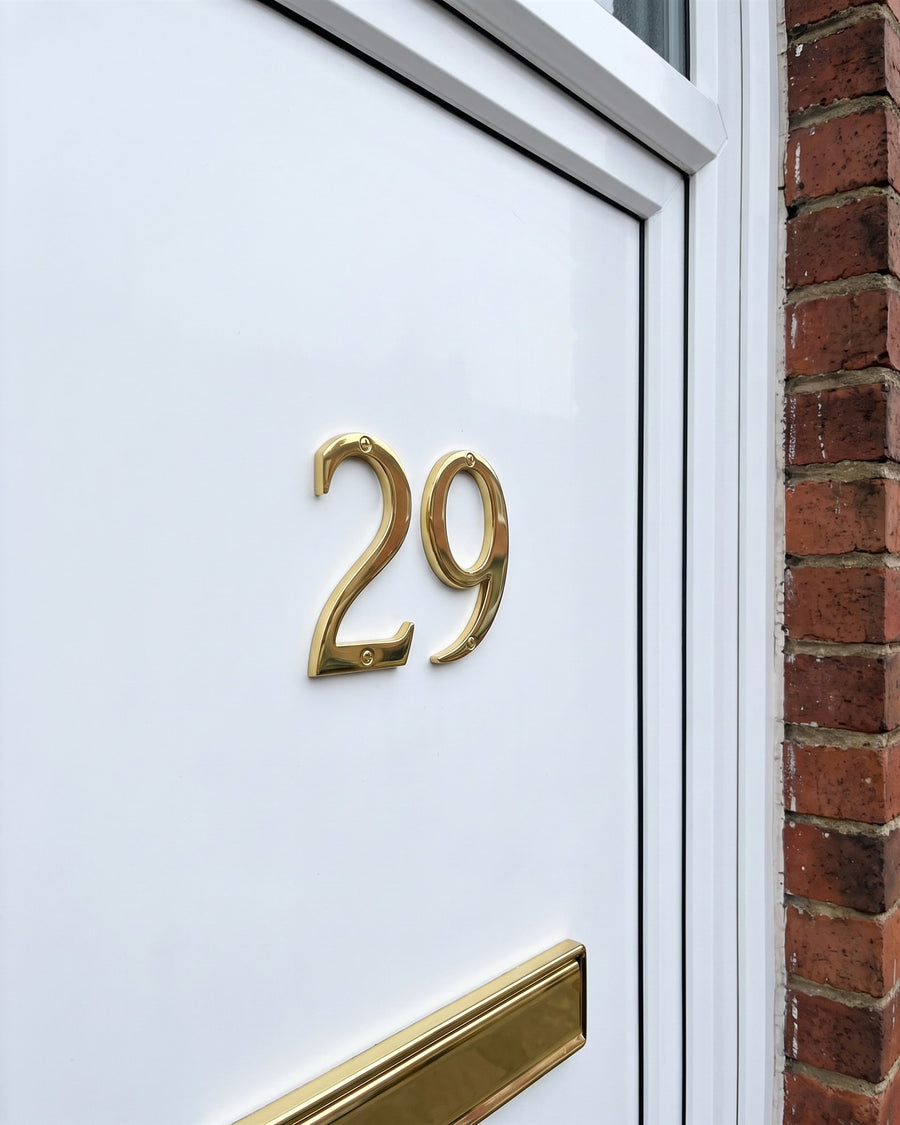 Slim gold-finish Hardex house numbers 29 surface-fixed to a white uPVC front door above a gold letter plate