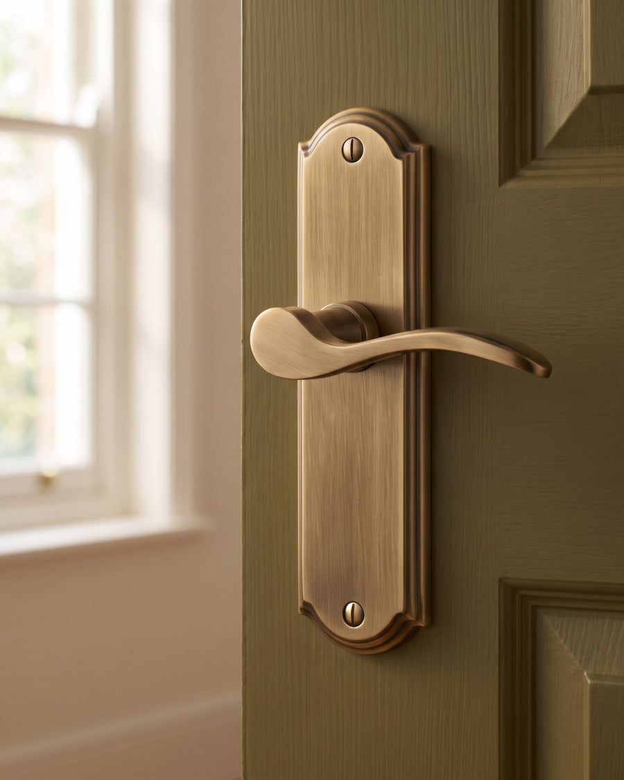 Antique brass Howard lever latch handle on an olive panelled door