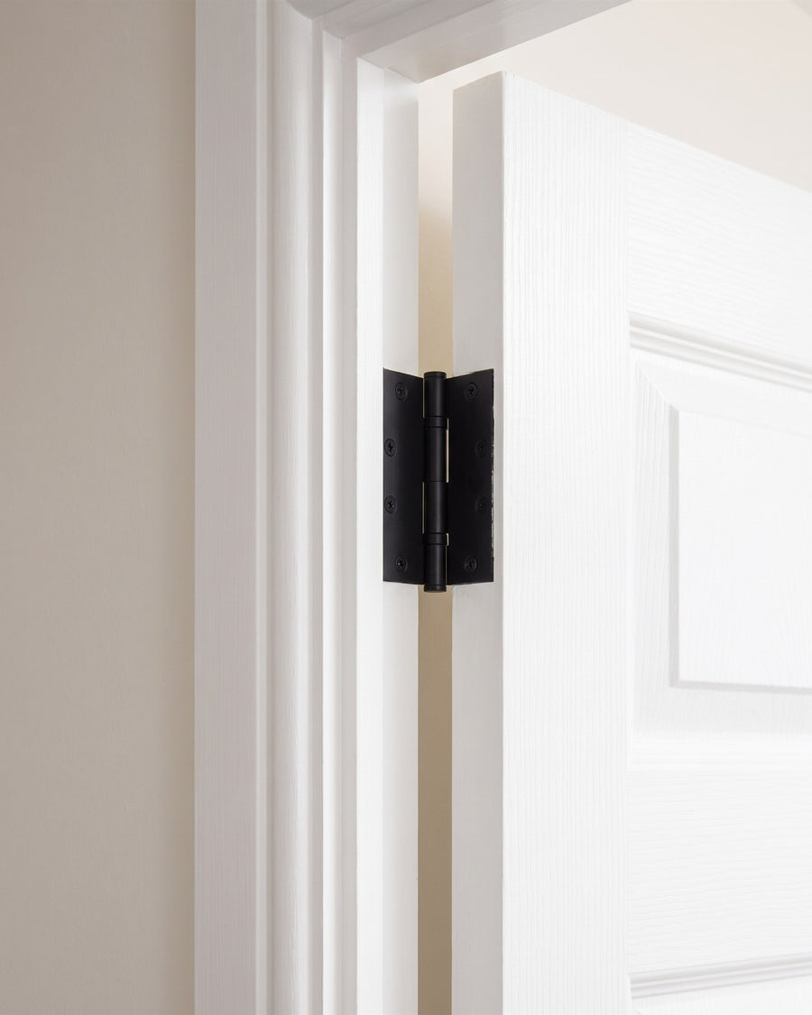 Matt black hinge joining a white moulded door to its frame