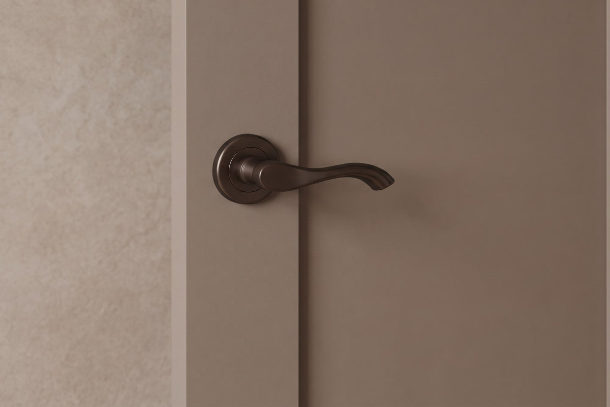 Matt bronze Algarve lever on rose handle on a mushroom-painted Shaker door, with a limewashed wall and pale oak hallway beyond
