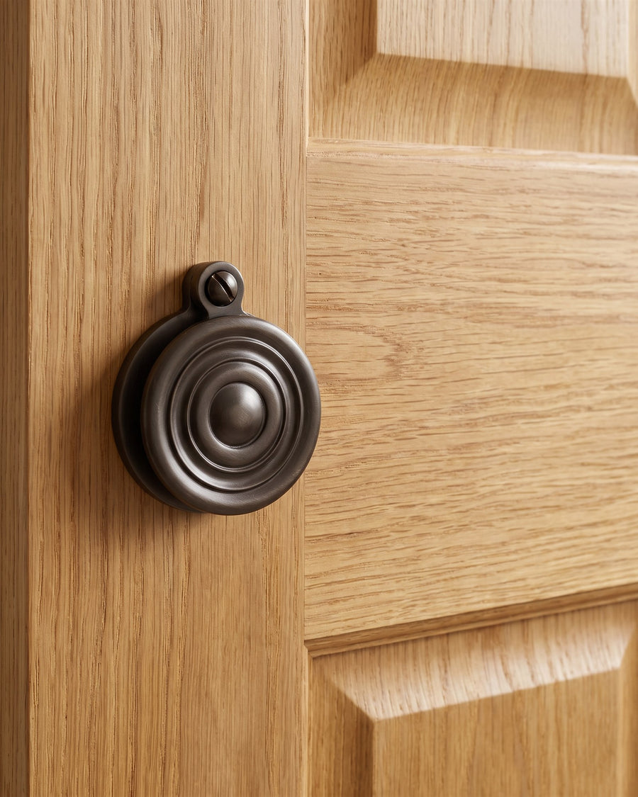 Matt bronze reeded covered escutcheon on the stile of a golden oak panelled door