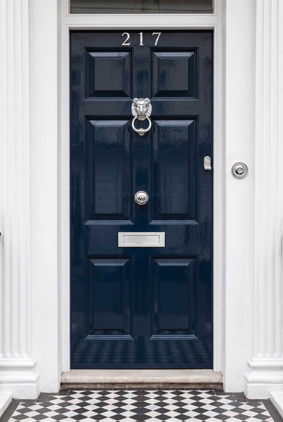 Navy gloss six-panel front door with polished chrome numbers, lion head knocker, centre knob, letter plate, cylinder pull and circular bell push