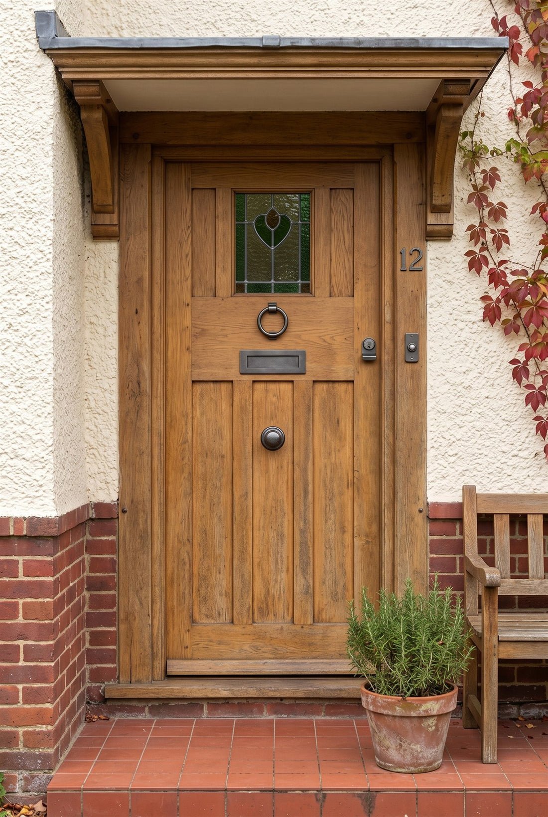 Honey oak Arts and Crafts front door with a heart leaded light under an oak porch canopy, fitted with a rustic pewter ring knocker, letter plate, centre knob, cylinder pull, bell push and house number