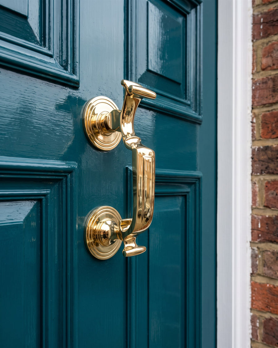 Polished brass doctor knocker and centre knob on a teal front door
