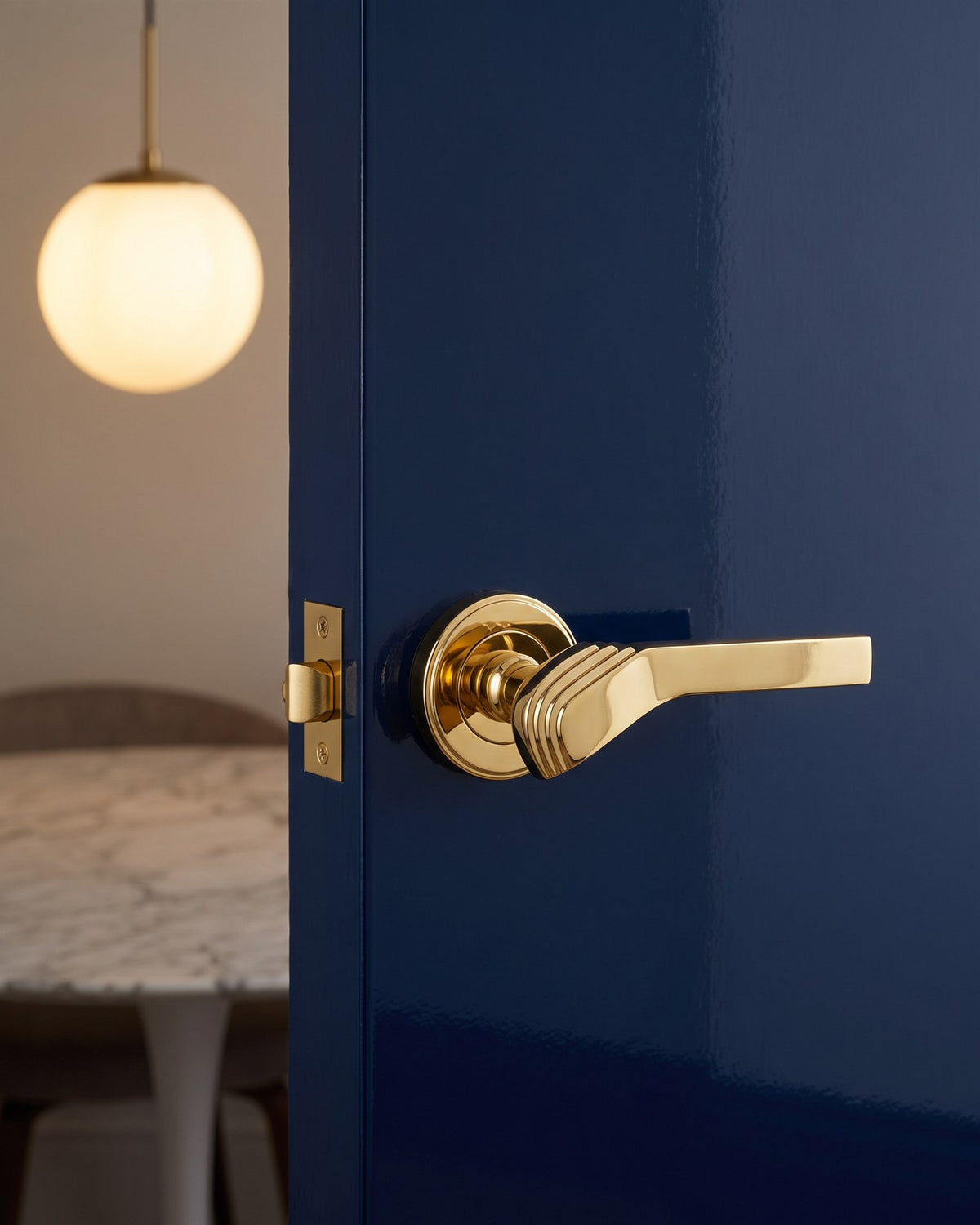 Polished brass Tiffany Art Deco lever on rose on an ink navy lacquered dining room door