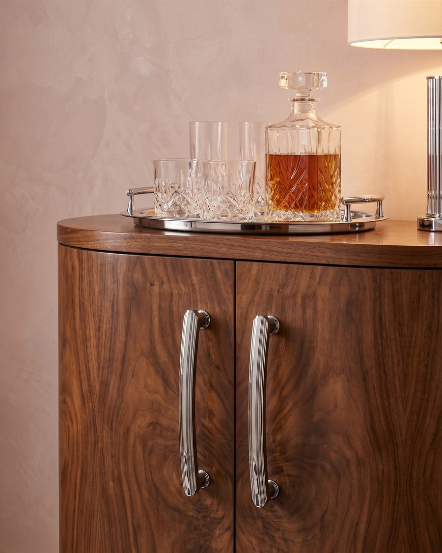 Polished chrome Art Deco cabinet handles on a curved burr walnut drinks cabinet with crystal decanter