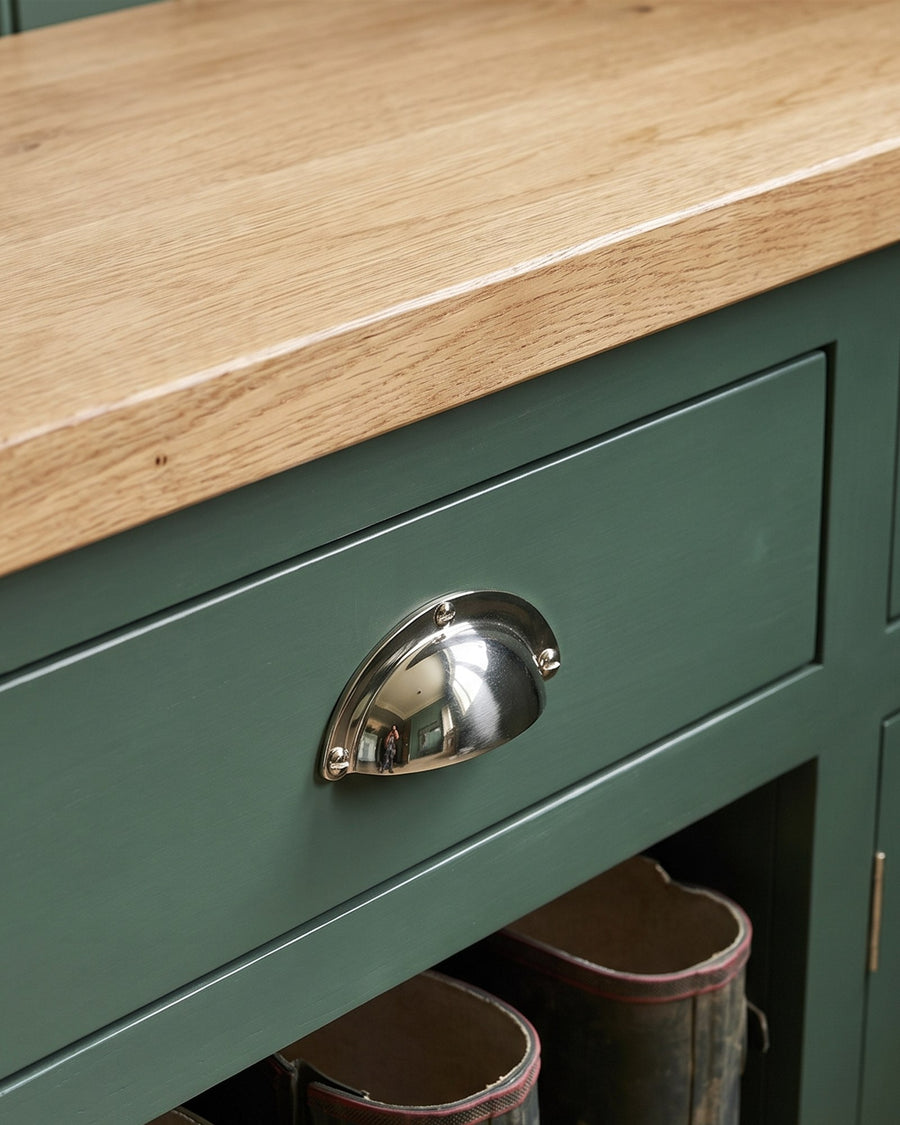 Polished nickel cup pull on a heritage green shaker drawer under an oak bench