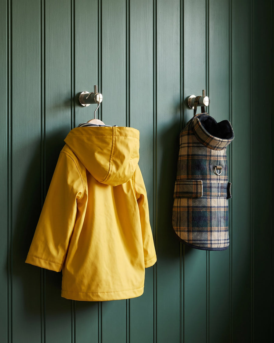 Polished nickel knurled coat hooks holding a yellow child's raincoat and a tartan dog coat on green panelling
