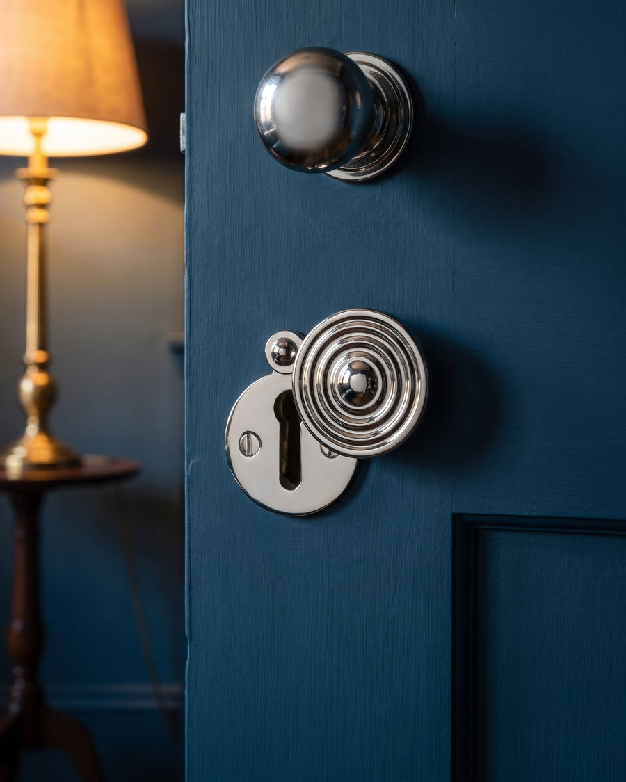 Polished nickel reeded covered escutcheon below a polished nickel mushroom knob on an ink blue door