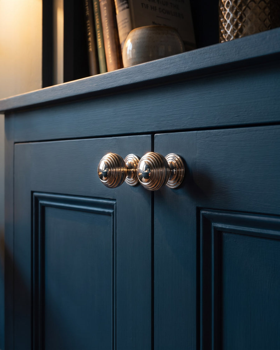 Pair of polished nickel reeded cupboard knobs on ink blue panelled alcove cupboard doors