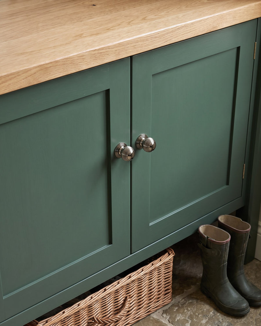 Polished nickel reeded cupboard knobs on a heritage green boot room cupboard