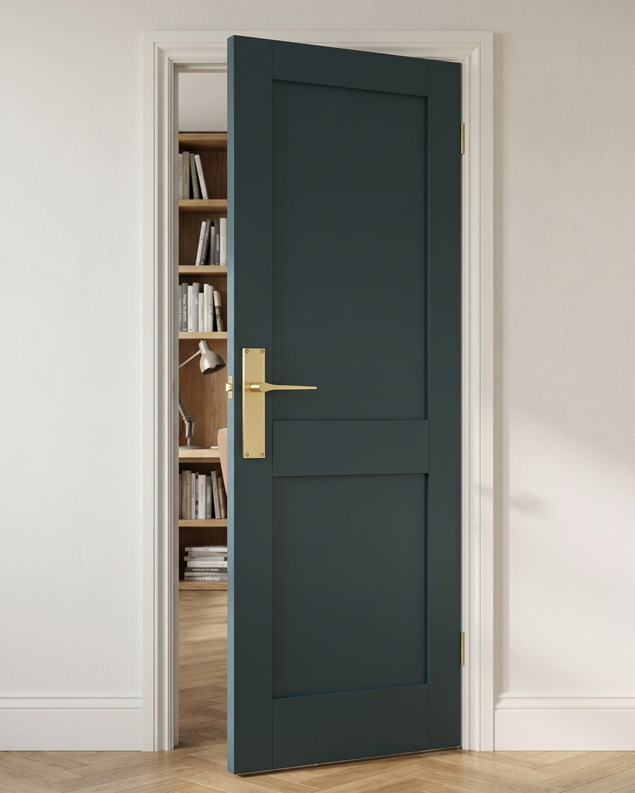 Deep inky blue-green Shaker study door with a satin brass reeded lever handle, oak bookshelves beyond