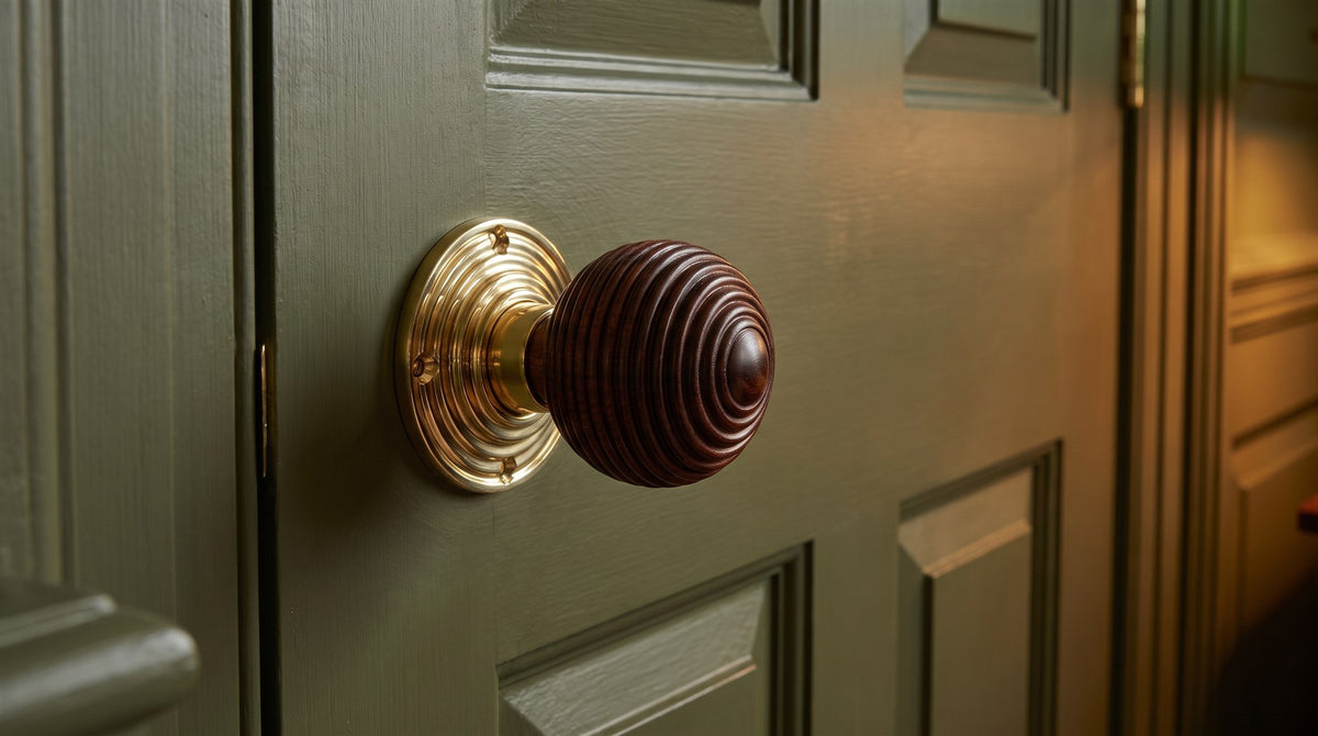 Turned rosewood beehive door knob on a polished brass reeded rose, on a deep olive green panelled door