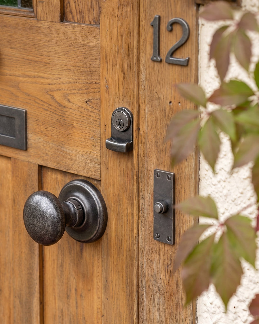 Rustic pewter centre knob and cylinder pull on an oak front door, with a pewter bell push and house number 12 on the oak frame