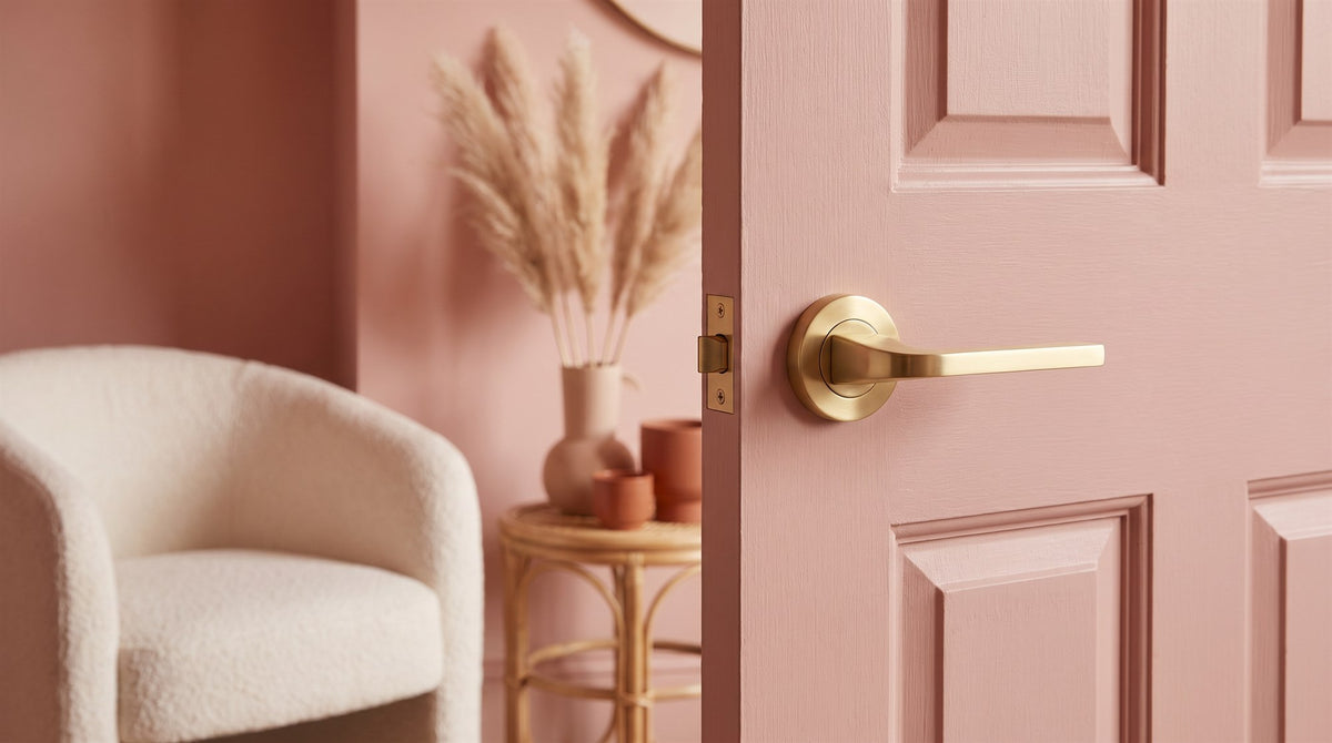Satin brass Bellagio lever on rose on a clay pink colour-drenched door