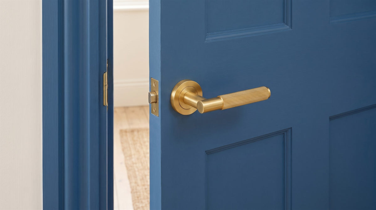 Satin brass Bloom lever with reeded bar on a round rose on a mid-blue painted panelled door