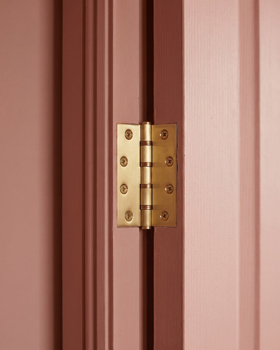 Satin brass butt hinge on a clay pink door and frame