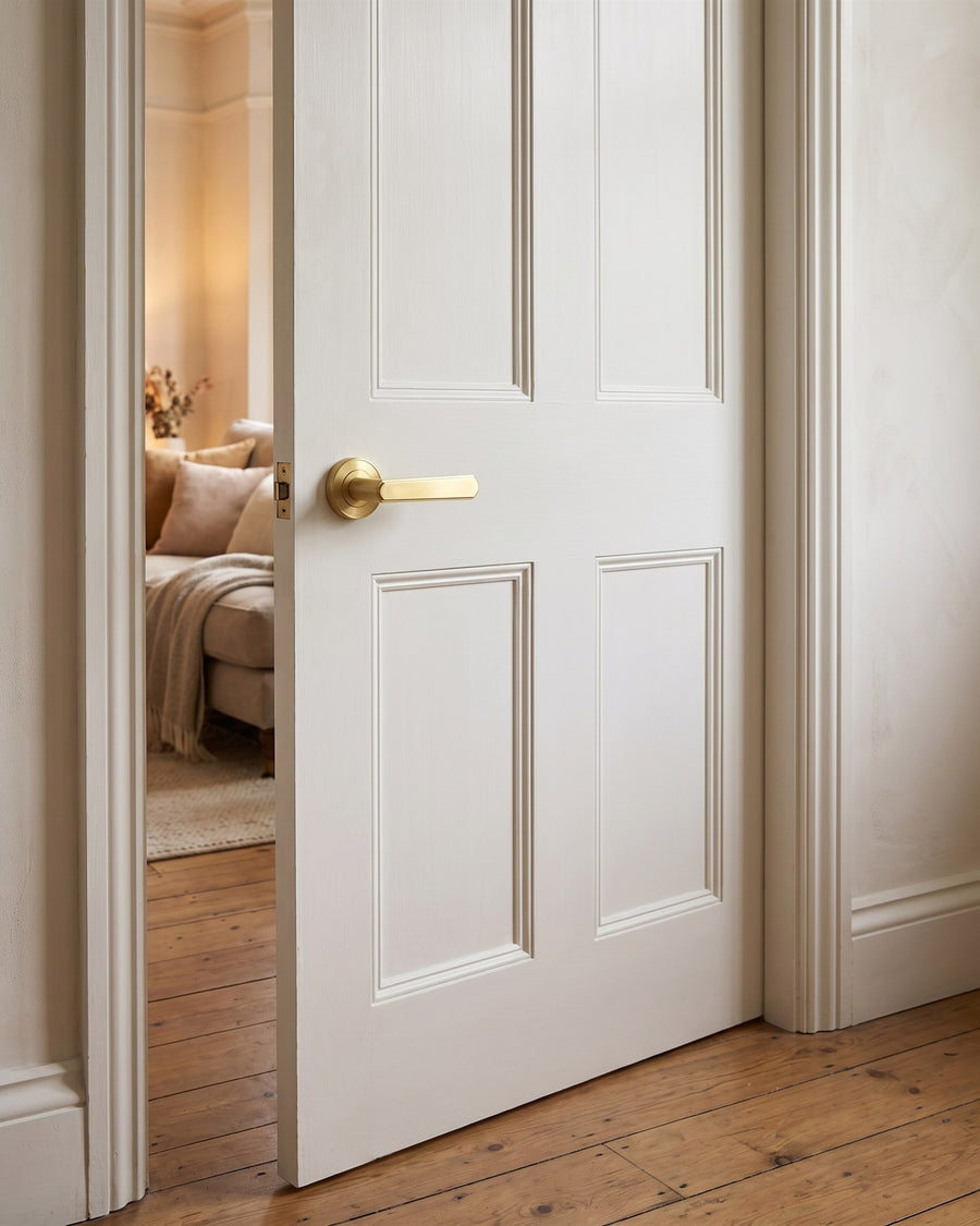 Satin brass Century lever on rose on a white panelled living room door in a Victorian flat