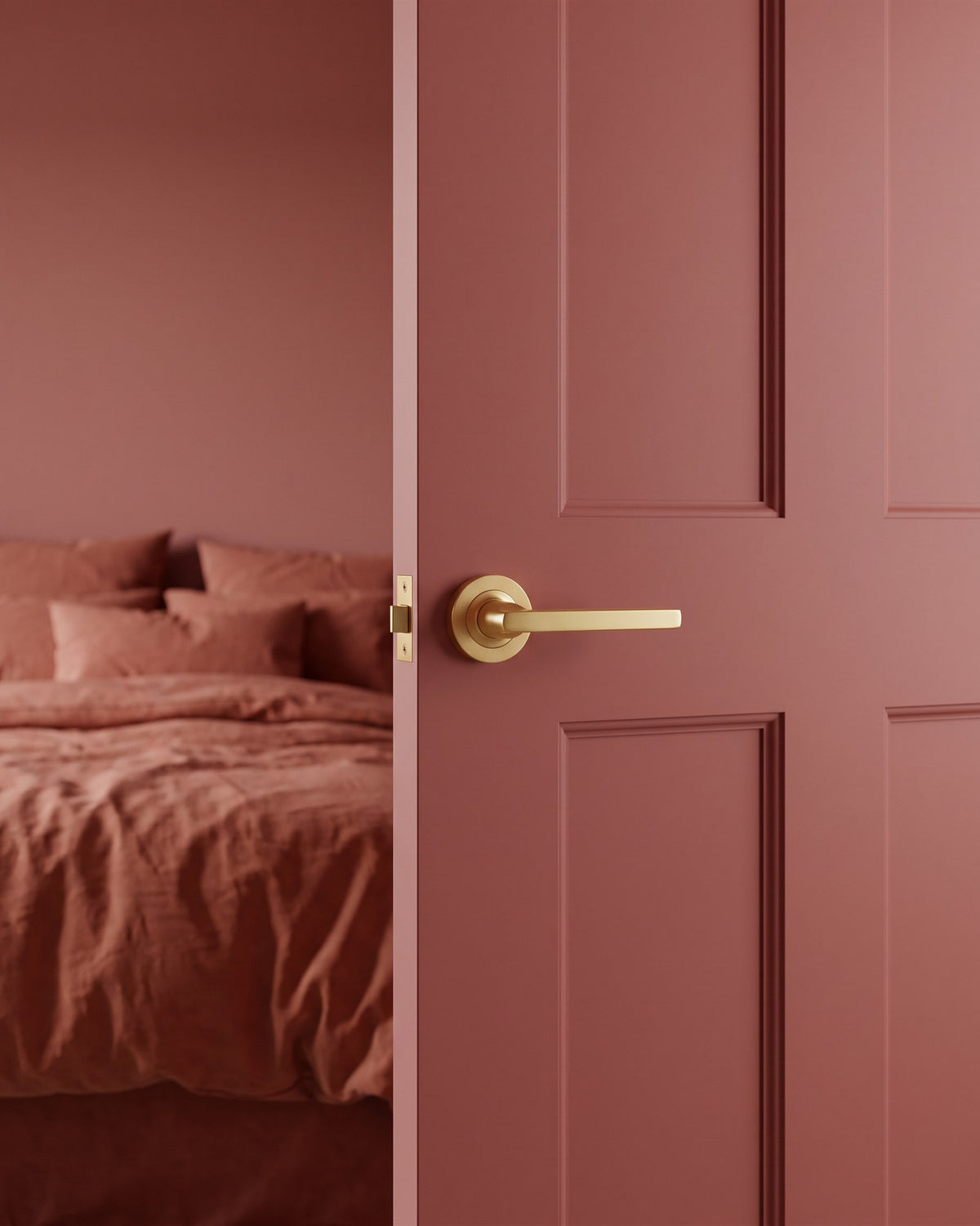 Satin brass Jet lever on rose on a rose-earth pink bedroom door, terracotta bedding beyond