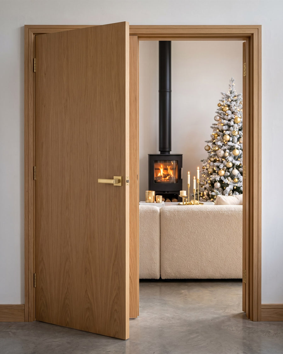 Satin brass linear lever on rose on an oak internal door, open onto a living room with a lit wood burner and a white Christmas tree
