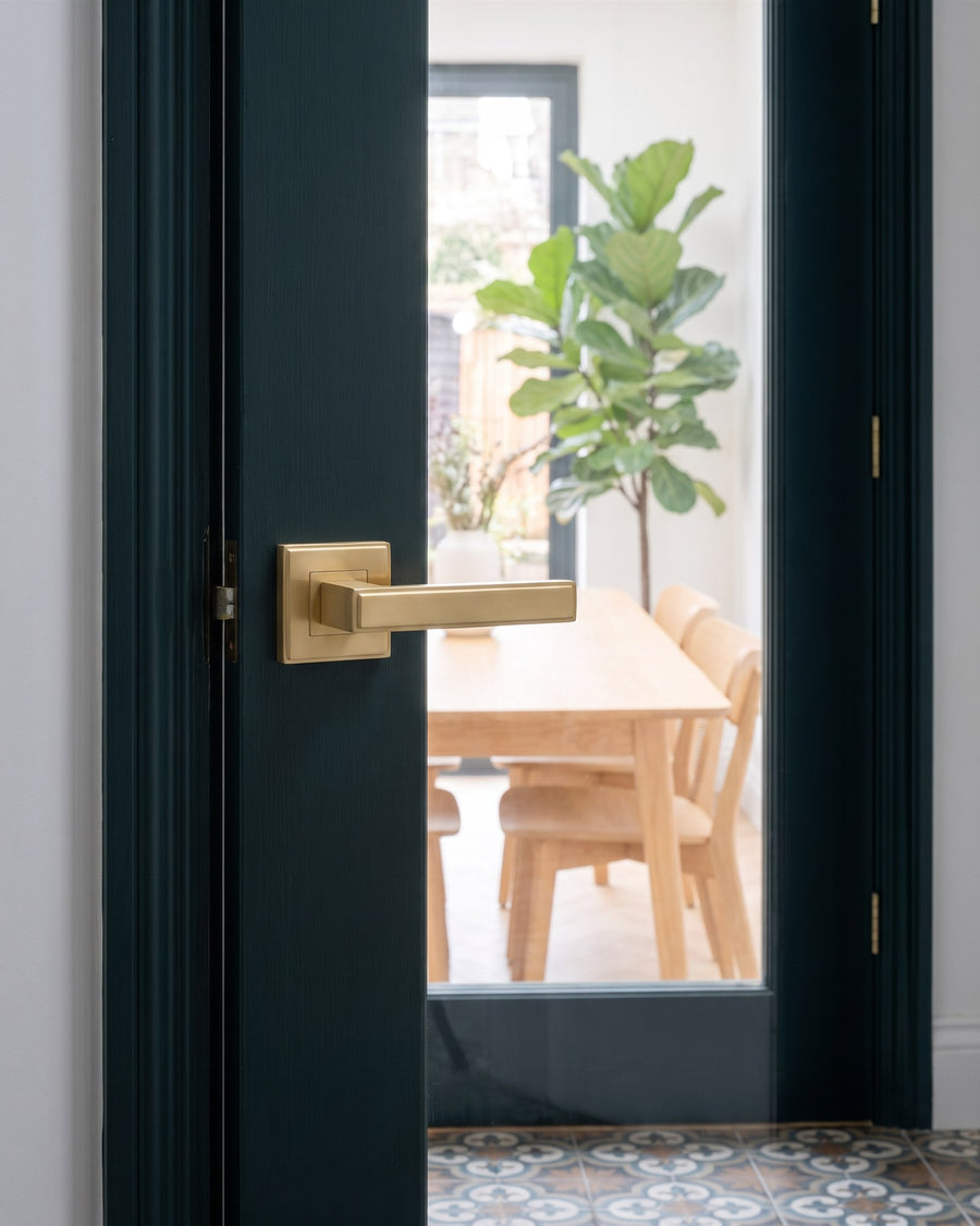 Satin brass linear lever on a square stepped rose on the narrow green stile of a glazed door into the extension