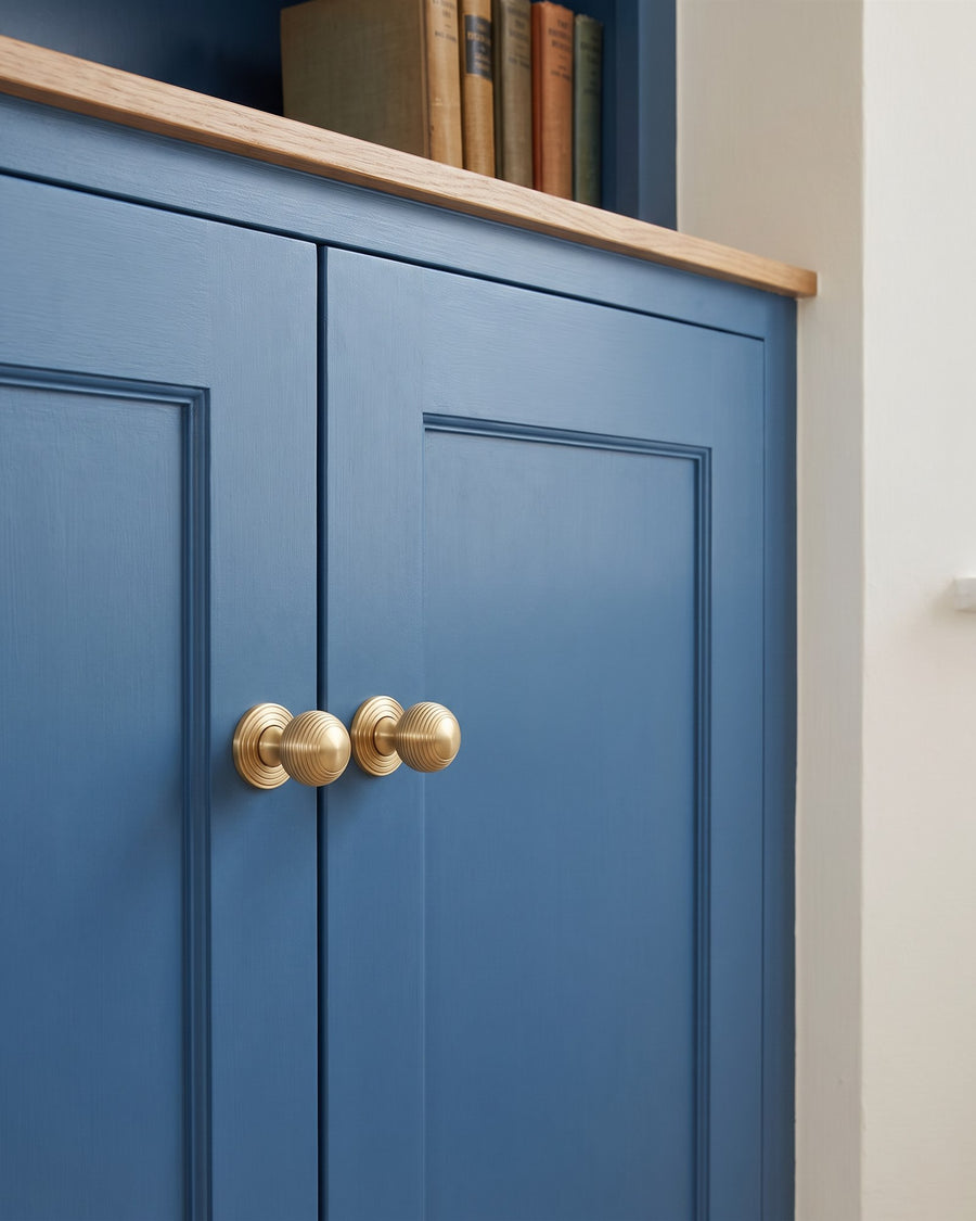 Satin brass reeded cabinet knobs on a mid blue painted alcove cupboard