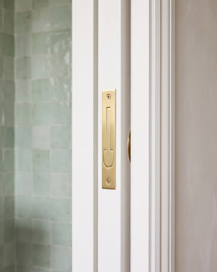 Satin brass sliding door edge pull set into the leading edge of a white pocket door