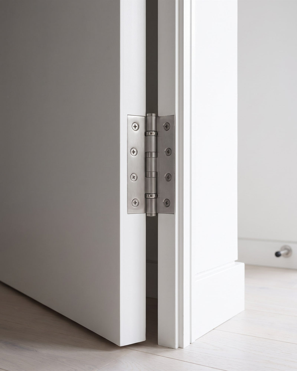 Satin chrome heavy duty ball-bearing butt hinge on the edge of a flush white door