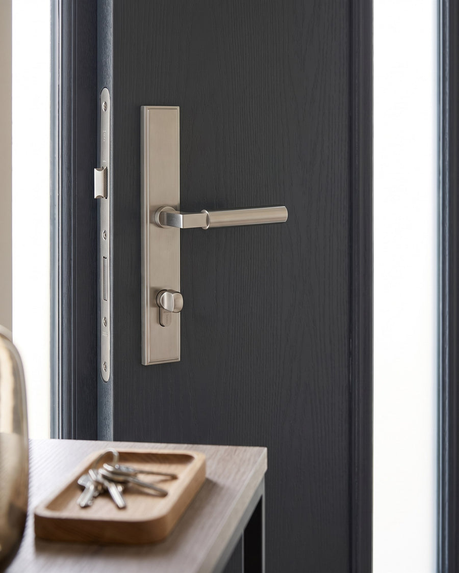 Satin nickel Bauhaus multipoint handle with a euro cylinder and thumbturn on the inside of an anthracite composite door, keys on an oak tray