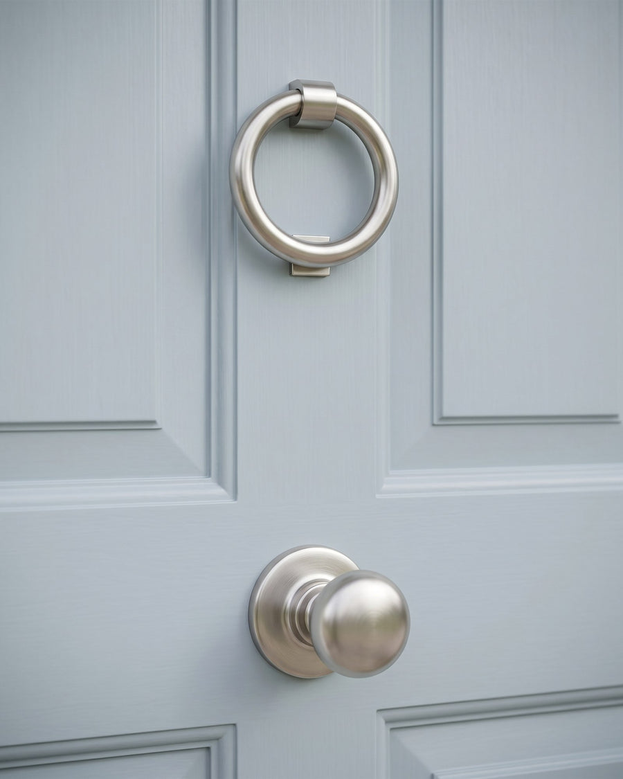 Satin nickel ring door knocker above a round satin nickel centre knob on a powder blue panelled front door