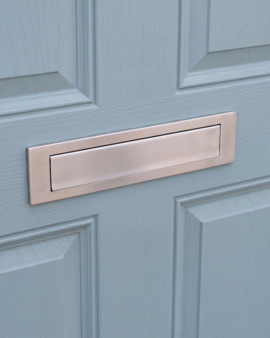 Satin stainless steel letter plate with its flap closed on a duck-egg blue composite door