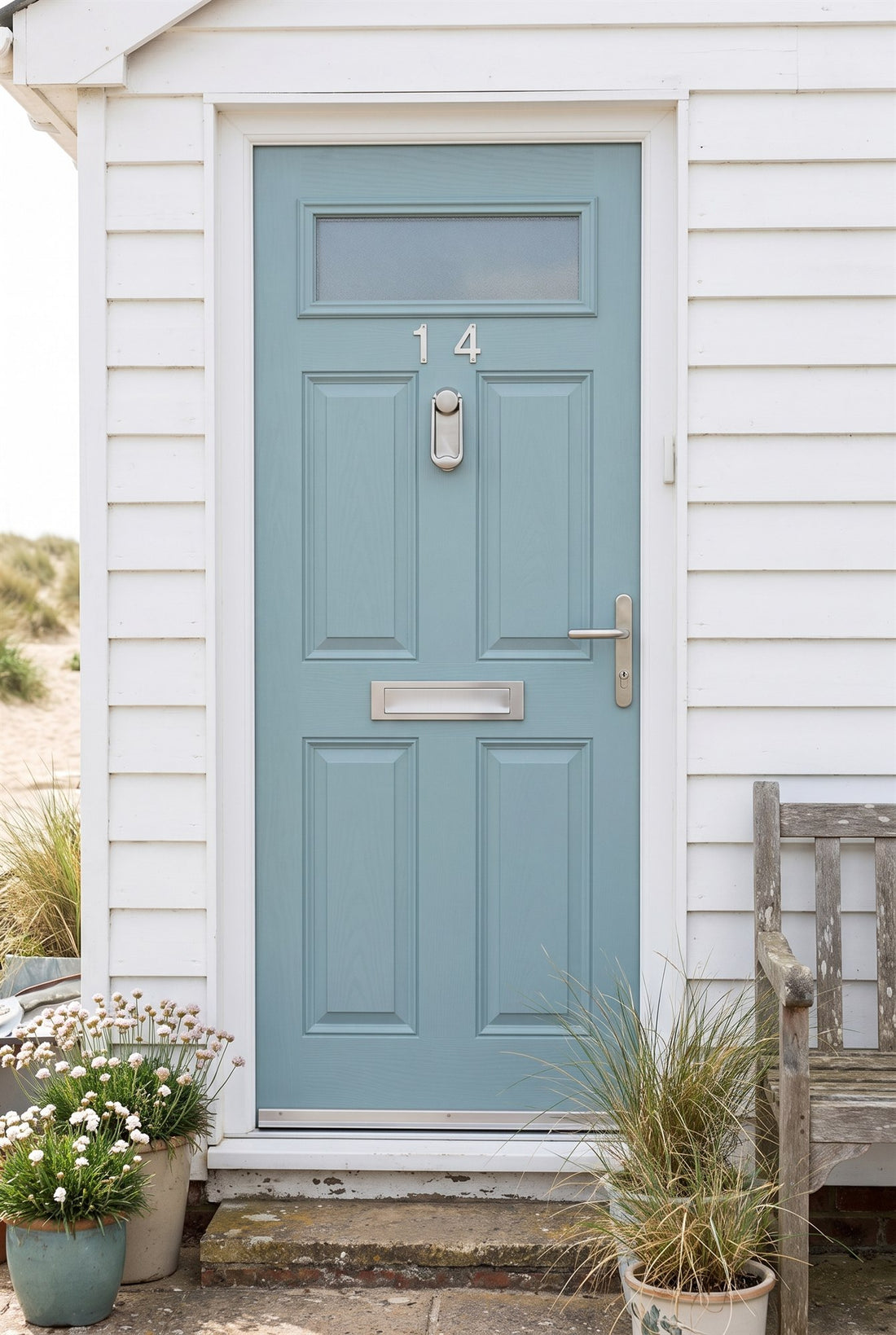 White weatherboard seaside cottage with a duck-egg blue composite door fitted with 316 stainless steel numbers, ingot knocker, letter plate, lever handle and threshold strip