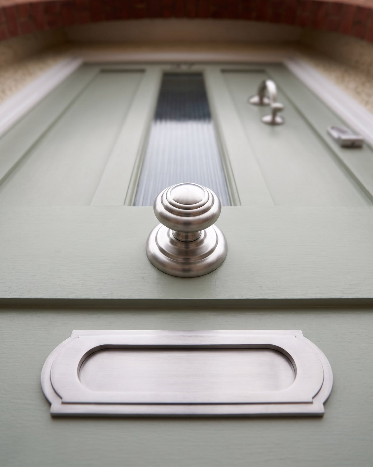 Satin chrome centre knob and letter plate on a sage front door